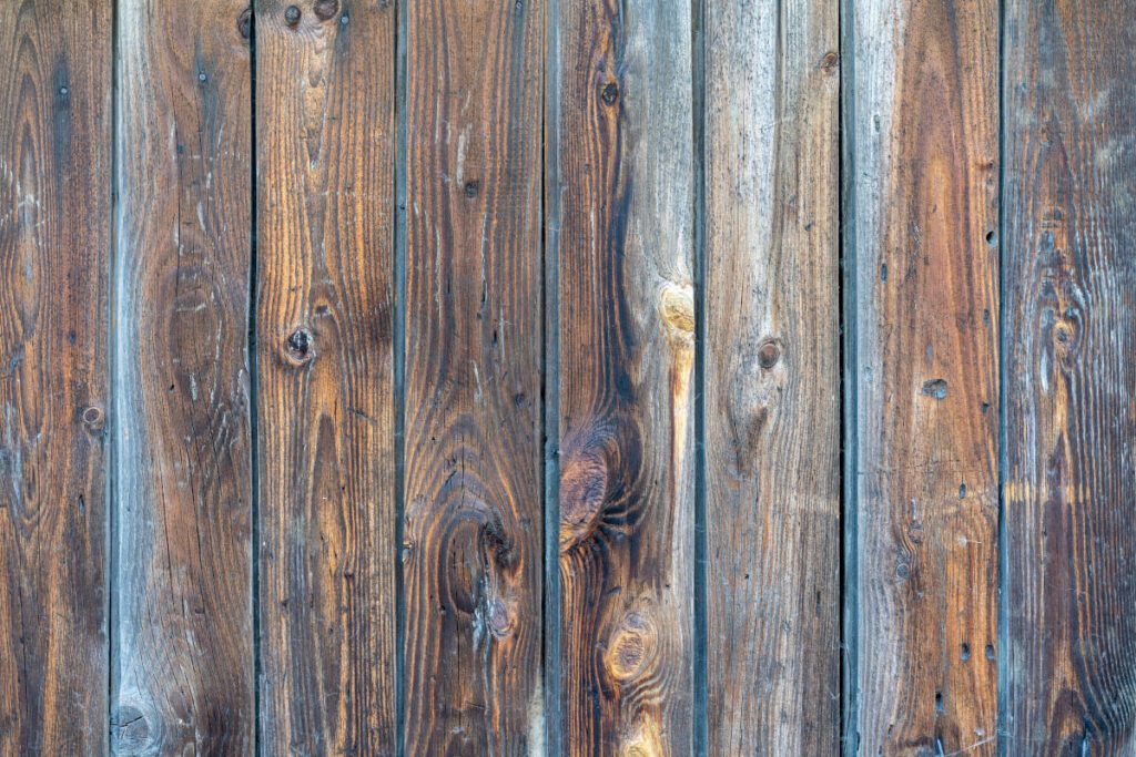 A closeup of a faded and stained wooden fence
