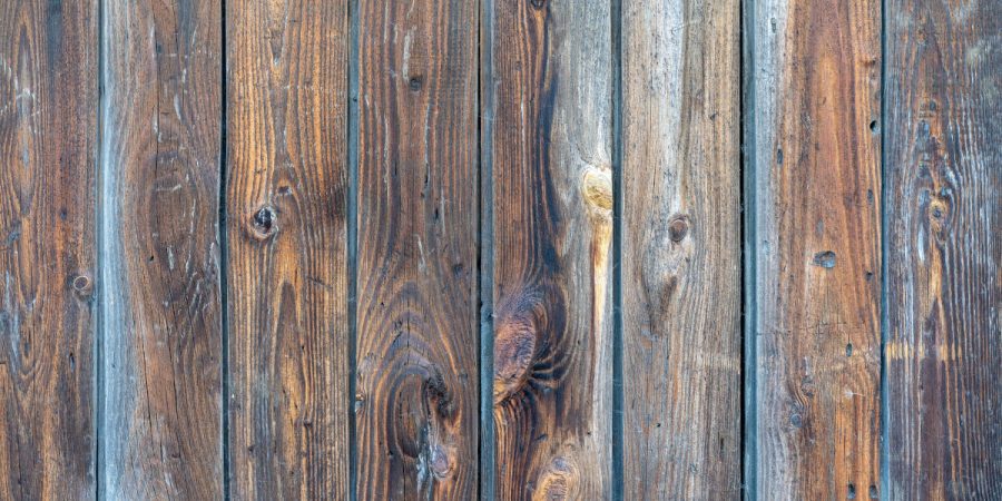A closeup of a faded and stained wooden fence